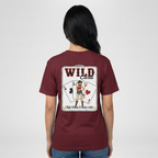Lifestyle photo of a woman wearing a burgundy t-shirt featuring a large “Wild Card” playing-card graphic on the back with western cowgirl illustration and card details, shown against a neutral background.